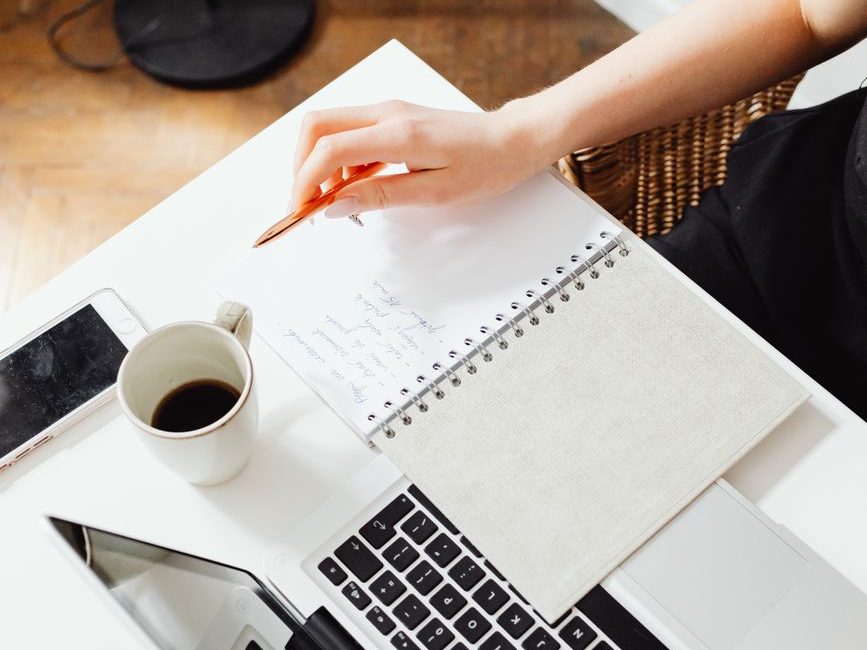 Notebook and laptop used to plan a monthly budget for living alone